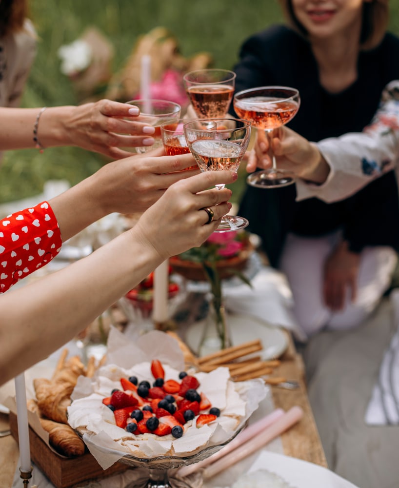 Women,Clink,Glasses,With,Rose,Wine,At,An,Outdoor,Party.